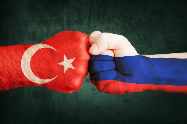 Closeup, flags on fist of Turkey against Syria on a black wall background. Concept of crisis of war and political conflicts between nations. — Stock Photo, Image