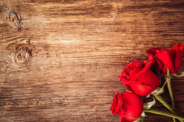 Sevgililer Günü için kırmızı güllerle çerçevelenmiş ahşap arka planlı süsler. Aşk ve aşk kavramı.