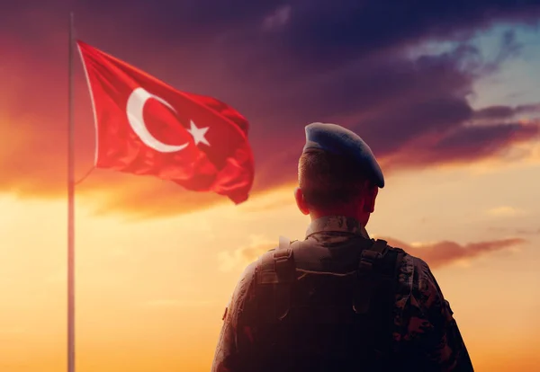 Турецкий солдат стоит и салютует перед турецким флагом на дежурстве . — стоковое фото
