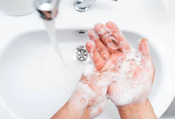 Igiene personale, pulizia mani con sapone spesso sul rubinetto per proteggere dal virus . Fotografia Stock