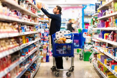 Tam alışveriş arabası, küresel kaos yüzünden müşteri hayati ihtiyaçlarını karşılıyor. Bulanık süpermarket ürünleri, iç plan alışverişi.