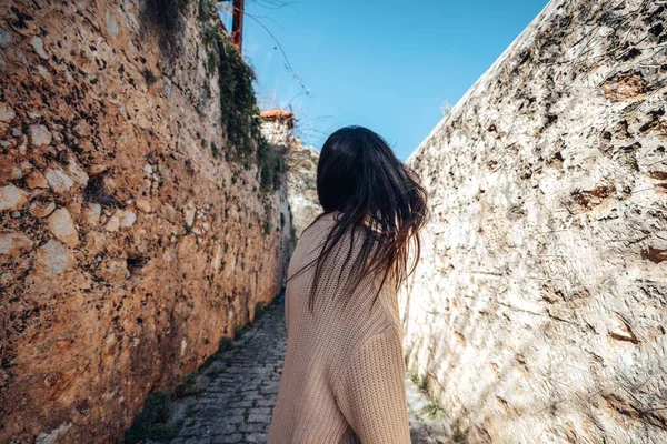 Mujer misteriosa joven está caminando entre paredes históricas en un callejón estrecho . — Foto de Stock