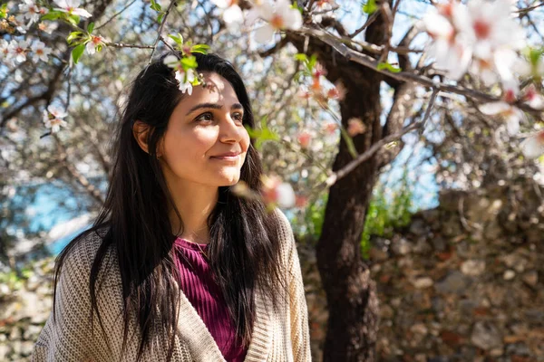 Mujer joven disfrutando de la vista y la luz del sol en su cara bajo el ciruelo con flores . — Foto de Stock