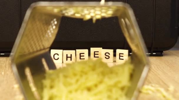 The camera zooms in on the inscription cheese through a metal grater — ストック動画