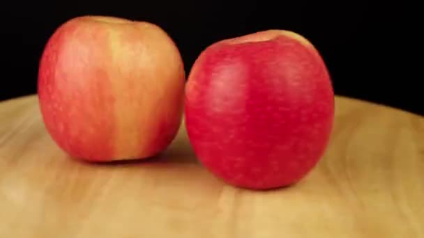 Dos manzanas rojas giran 360 grados en un soporte de madera — Vídeo de stock