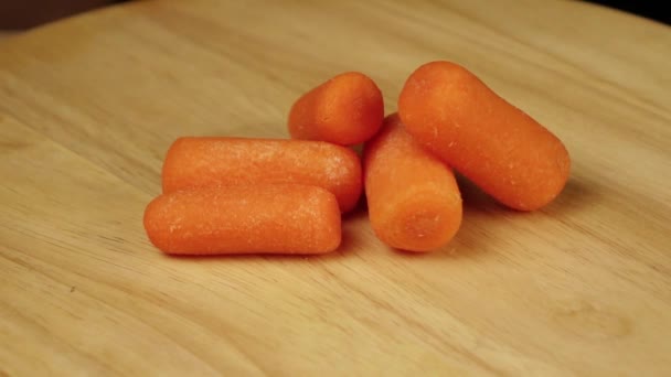 Un sacco di piccole carote ruotano 360 gradi su una piattaforma di legno — Video Stock