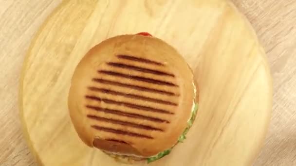 Wirujący hamburger na drewnianym stojaku widok z góry — Wideo stockowe
