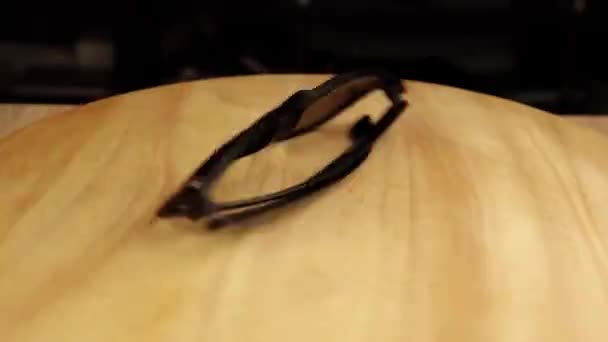 Gafas de sol oscuras girando 360 grados en un soporte de madera — Vídeo de stock