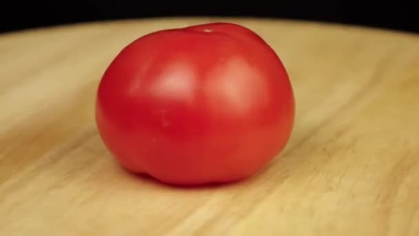 Red tomato rotates 360 degrees on a wooden platform — ストック動画