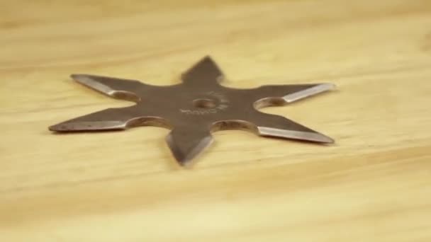 shuriken argent tourne à 360 degrés sur un support en bois 