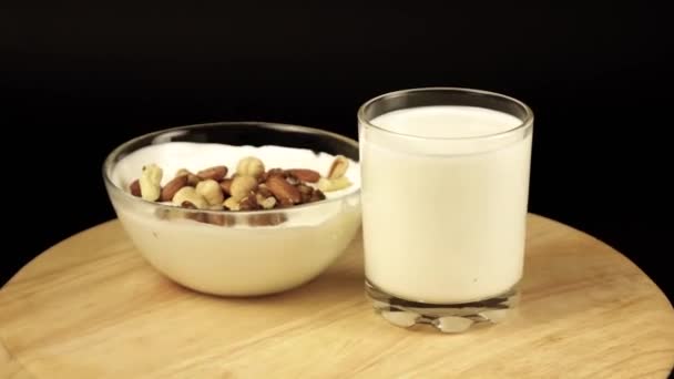 Ett glas mjölk och en tallrik yoghurt med nötter rotera 360 grader — Stockvideo