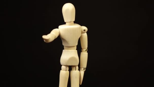 The wooden doll pulls its arm forward and rotates 360 degrees on a black background — Stock Video