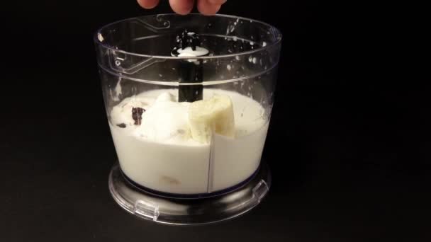 A mans hand pours raisins into the milk mixture in a blender — Stock Video