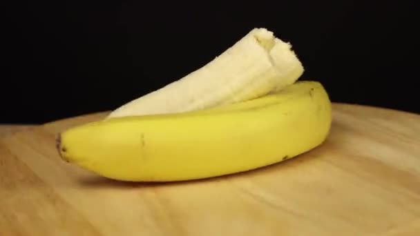 Два банана одно целое и одно без кожуры вращаются на 360 градусов — стоковое видео