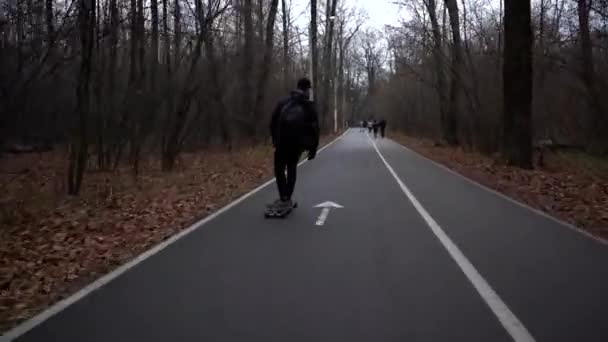 Moskva Rusko 24 října 2019. muž v černém jezdí na longboardu na dálnici v parku. — Stock video