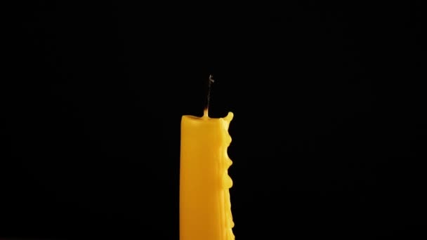 Ręka zapala zapałkę żółta świeca na czarnym tle — Wideo stockowe
