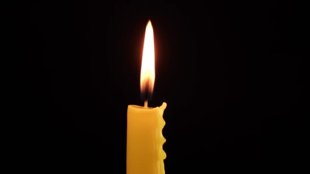 Рука зажигает спичечную желтую свечу на чёрном фоне — стоковое видео