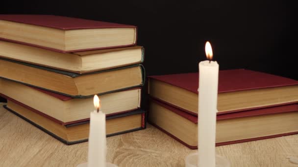 Libros se colocan uno encima del otro a la luz de las velas — Vídeos de Stock