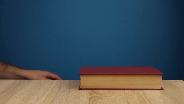 Hand puts the books on top of each other on a blue background. Education and learning concept. — Stock Video