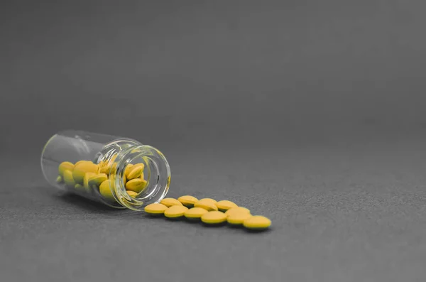 scattered yellow pills from a glass flask. black and white photo