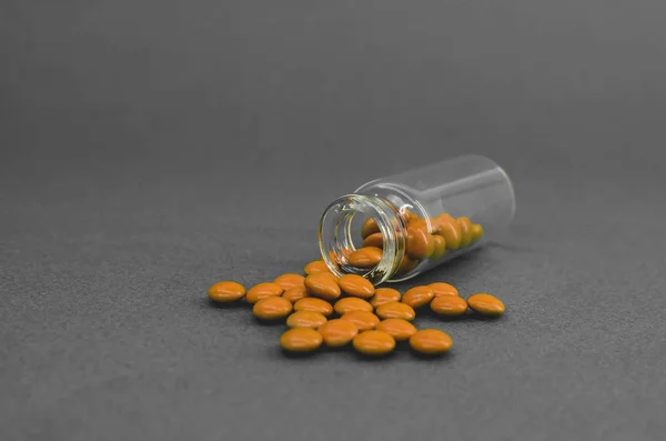 Розкидані апельсинові таблетки зі скляної колби. на чорно-білому тлі — стокове фото