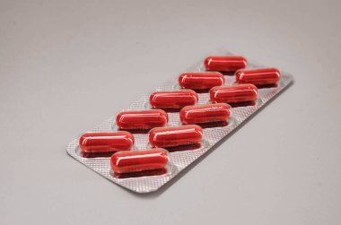 Bir paket kırmızı kapsül tablet, on parça halinde. Yukarıdan görünüm.