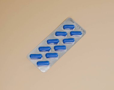 bir paket mavi kapsül tableti bej arka planda on parça olarak