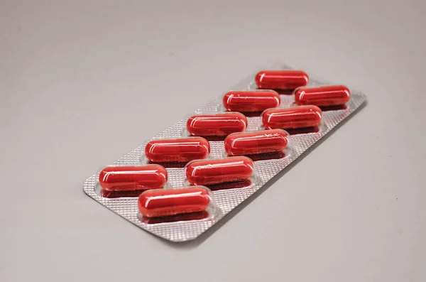 Envase de cápsulas-comprimidos rojos en la cantidad de diez piezas. la vista desde la parte superior . —  Fotos de Stock