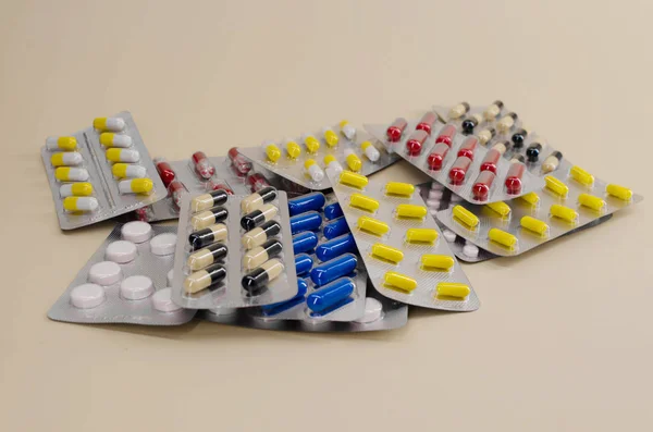 Ένα μάτσο χάπια και βιταμίνες σε συσκευασίες που βρίσκονται σε ένα μπεζ φόντο — Φωτογραφία Αρχείου