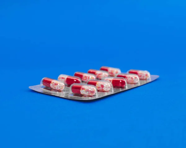 Tabletas de la cápsula en un paquete sobre un fondo azul . — Foto de Stock