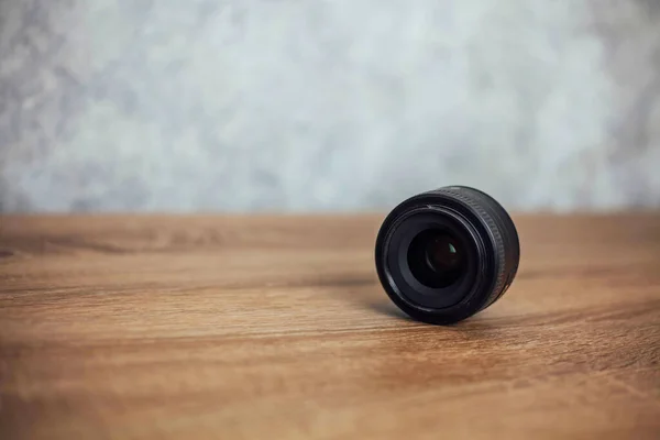 Zwarte lens ligt zijdelings op een houten achtergrond — Stockfoto