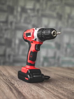 Kırmızı elektrikli tornavida, ahşap masaya yakın duruyor..