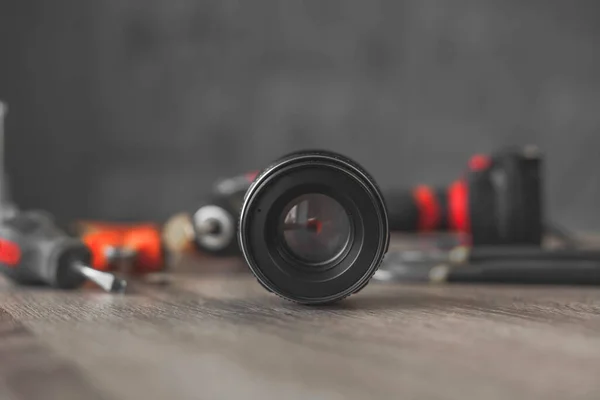 Zwarte lens van de camera ligt tussen een stapel gereedschap — Stockfoto