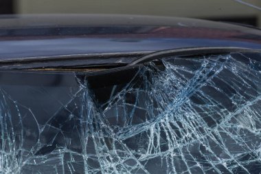 Bir arabanın sokağında duran kırık bir ön cam.