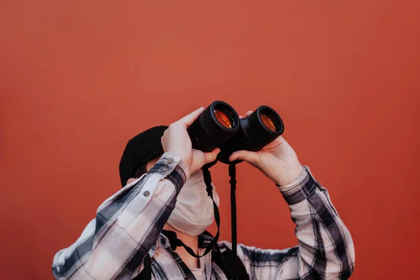 Un bărbat se uită în sus prin binocluri pe un fundal roșu — Fotografie, imagine de stoc