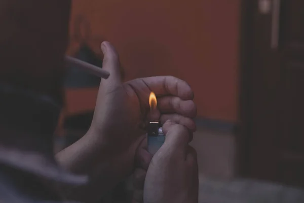 Un hombre enciende un cigarrillo por la noche Imagen De Stock