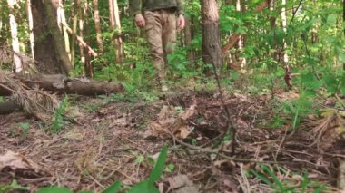 Bir adam ormanda çimlerin üzerinde yalınayak yürür.