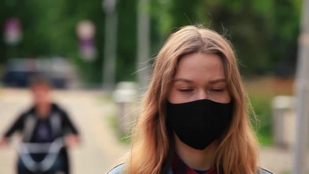 Ein Mädchen mit schwarzer Maske steht auf der Straße — Stockvideo