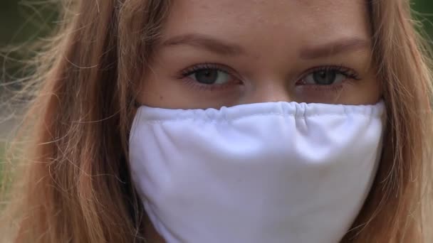 Una chica con una máscara blanca está de pie en la calle. de cerca — Vídeo de stock