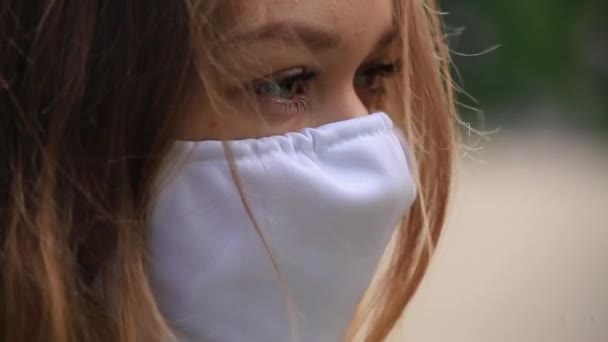 Una ragazza con una maschera bianca è in piedi sulla strada. vista laterale — Video Stock