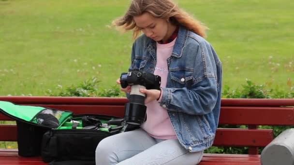 Een meisje zit op een bank en past haar camera Moskou, Rusland mei 20, 2020 — Stockvideo