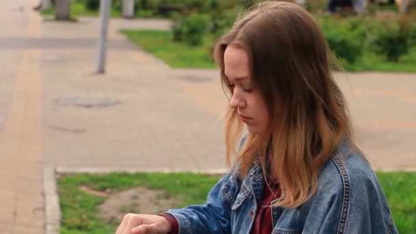 Flicka sitter i parken dricksvatten — Stockvideo