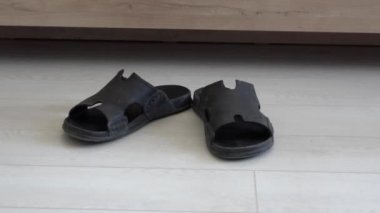 Erkek ayakları parmak arası terlikleri giyip gider.