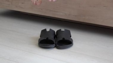 Adam siyah terliklerini giyer ve gider.