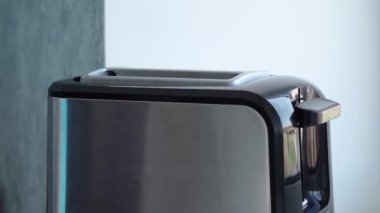 Adam ekmek kızartma makinesine taze ekmek koyar ve onu çalıştırır.