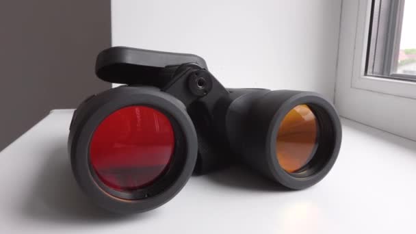 Black optical binoculars lie on the white windowsill — Stock Video