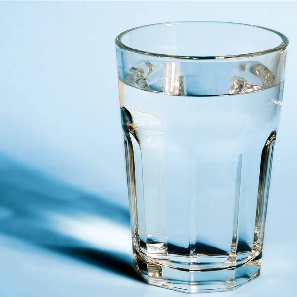Wasserglas mit starken Schatten auf weißem Hintergrund — Stockfoto