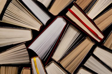 Kitaplar. Birçok renkli, kalın, açık kitap karanlık bir arka planda duruyor.
