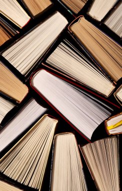 Kitaplar. Birçok renkli, kalın, açık kitap karanlık bir arka planda duruyor.