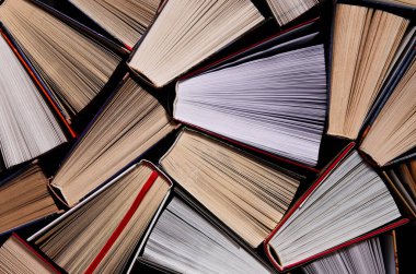 Kitaplar. Birçok renkli, kalın, açık kitap karanlık bir arka planda duruyor.